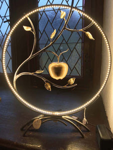 Lampe a poser avec ruban led cercle acier agrémenté de feuilles laiton avec pomme en volume au centre