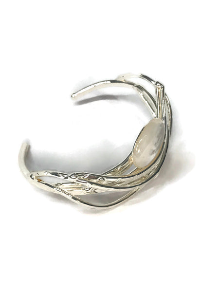 bracelet en laiton argenté, courbes de métal enserrant une nacre véritable, sur environ 2,5 cm de large, vue de biais