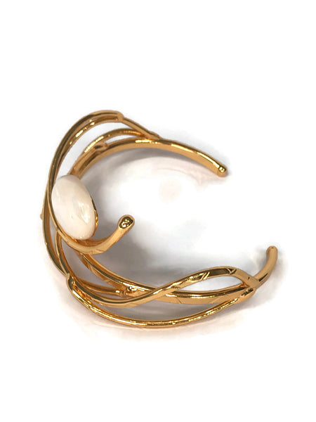 bracelet en laiton doré, courbes de métal enserrant une nacre véritable, sur environ 2,5 cm de large, vue de biais