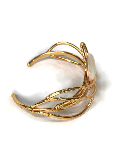 bracelet en laiton doré, courbes de métal enserrant une nacre véritable, sur environ 2,5 cm de large, vue de côté