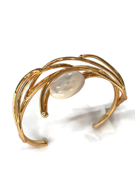bracelet en laiton doré, courbes de métal enserrant une nacre véritable, sur environ 2,5 cm de large, vue de dessus