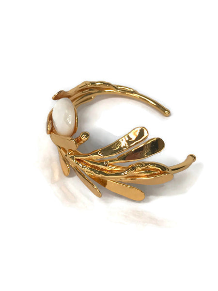 bracelet de créateur, doré, motif végétal, petites feuilles assemblées qui capte la lumière, cabochon de nacre au centre,vue de côté