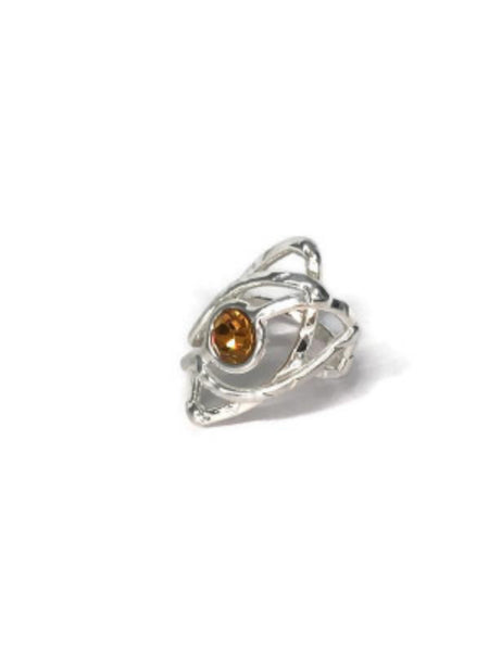 bague en laiton argenté avec strass au centre, 3cm de large environ, le métal s'allonge autour du strass et forme une légère pointe, vue de face