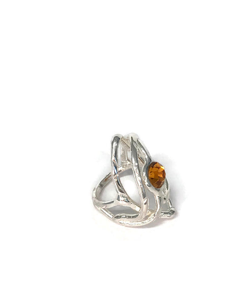 bague en laiton argenté avec strass au centre, 3cm de large environ, le métal s'allonge autour du strass et forme une légère pointe, vue de biais