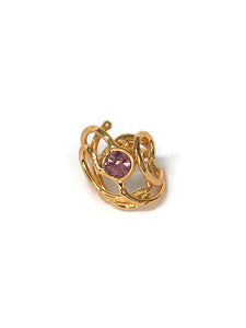 Bague en laiton doré, composée de circonvolutions et courbes autour d'un strass améthyste, vue de biais