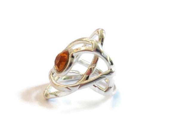 bague en laiton argenté avec strass au centre, 3cm de large environ, le métal s'allonge autour du strass et forme une légère pointe, vue de côté