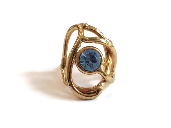 bague en laiton doré avec strass au centre, 2,5 cm de large environ, formée d'entrelacs courbés, vue de face