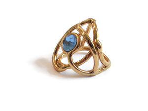 bague en laiton doré avec strass au centre, 2,5 cm de large environ, formée d'entrelacs courbés, vue de biais