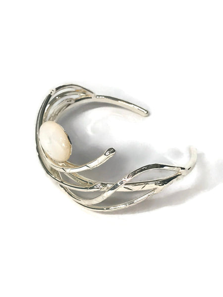 bracelet en laiton argenté, courbes de métal enserrant une nacre véritable, sur environ 2,5 cm de large, vue de côté