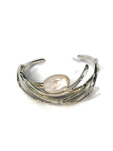 bracelet en laiton argenté, courbes de métal enserrant une nacre véritable, sur environ 2,5 cm de large, vue de face