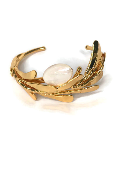 bracelet de créateur, doré, motif végétal, petites feuilles assemblées qui capte la lumière, cabochon de nacre au centre,vue de face