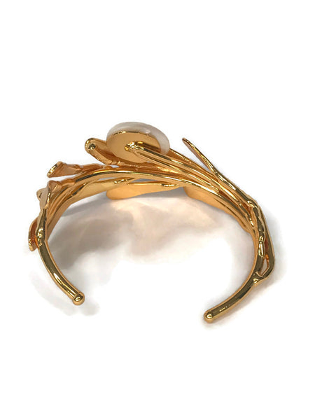 bracelet de créateur, doré, motif végétal, petites feuilles assemblées qui capte la lumière, cabochon de nacre au centre,vue de dos