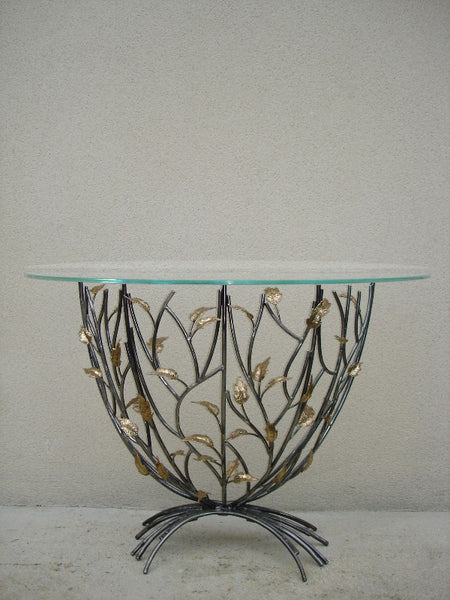 console en forme de demi-lune, plateau de verre porté par un entrelacs de tiges d'acier ornées de feuilles en laiton, vue d'ensemble