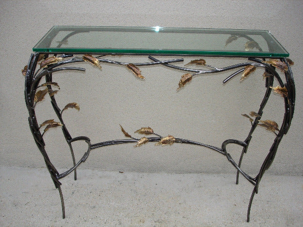 console rectangulaire, plateau de verre porté par un entrelacs de tiges d'acier ornées de feuilles en laiton, vue de face
